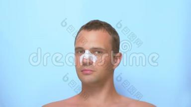整容的概念，一个男人做完整容后的脸，隆鼻，用绷带包扎鼻子.. 蓝色的